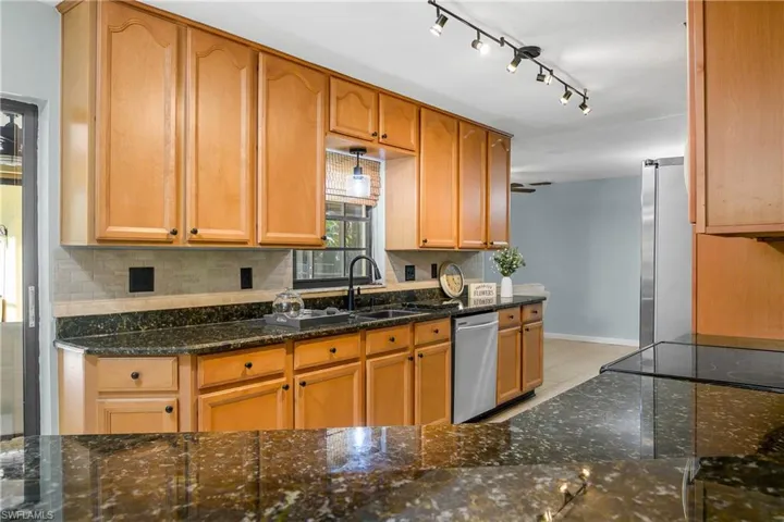 Kitchen featuring appliances with stainless steel finishes, backsplash, dark stone countertops, and light tile patterned flooring