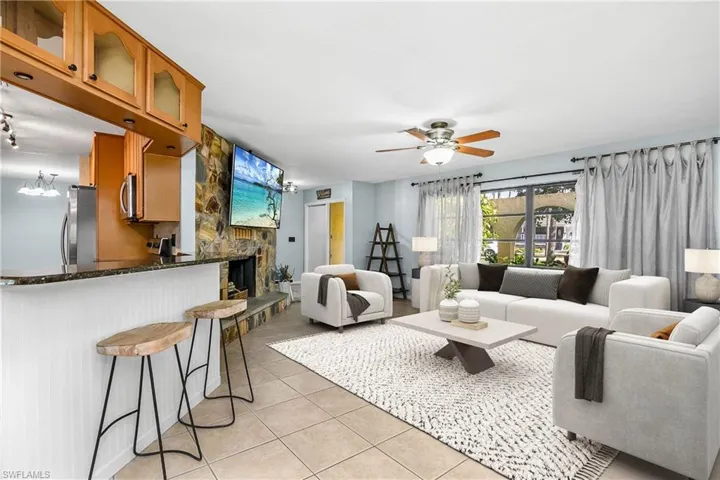 Living area featuring light tile patterned flooring, a ceiling fan, and a fireplace