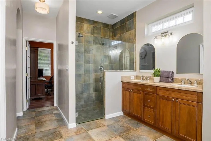 Master Bathroom featuring a shower stall, double vanity, and stone finish flooring