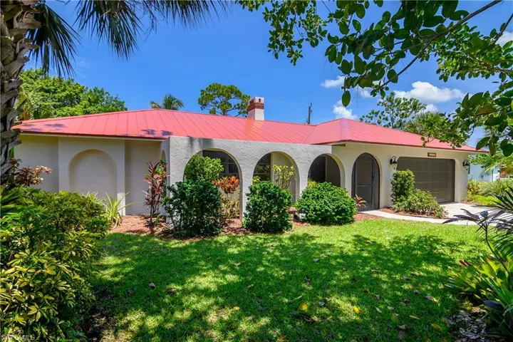 Freshly painted home featuring stucco siding, a metal roof, a front yard, a garage, and concrete driveway