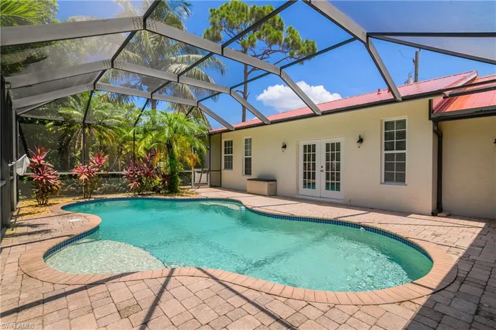 Swimming pool with french doors, a patio area, and a lanai