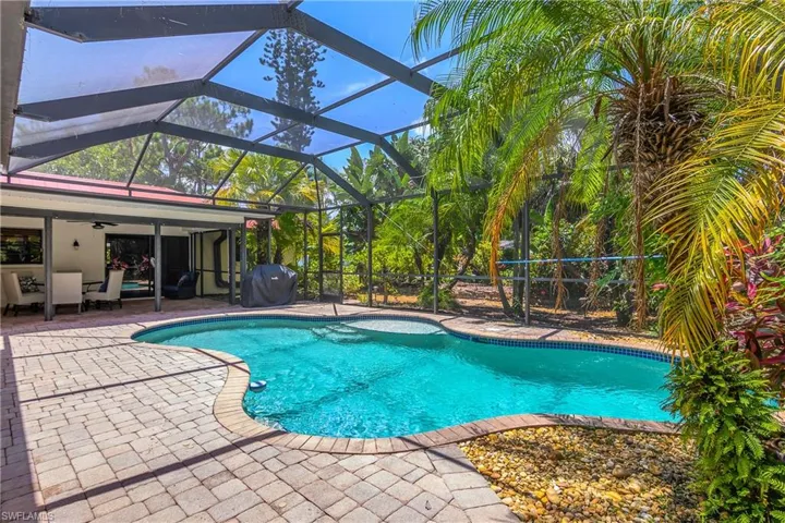 Swimming pool with a patio, ceiling fan, a grill, and glass enclosure