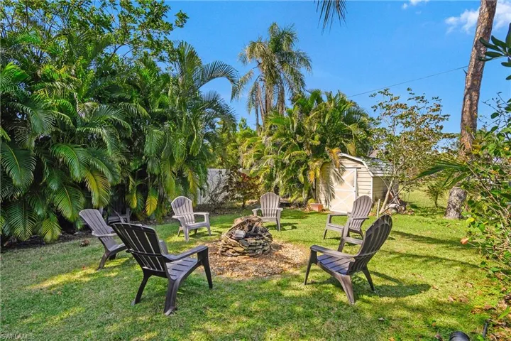 View of green lawn featuring a fire pit and a storage unit