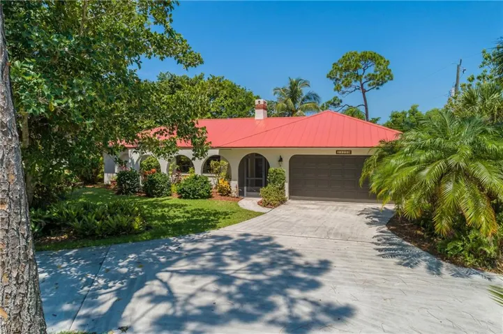 Freshly painted home featuring stucco siding, an attached garage, driveway, a chimney, and a metal roof