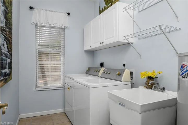 Laundry area with cabinet space, washing machine and clothes dryer, plenty of natural light, and light tile patterned flooring