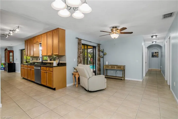 Kitchen with light tile patterned floors, arched walkways, a ceiling fan, dishwasher, and a chandelier