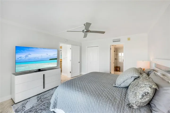 Bedroom featuring ensuite bath, crown molding, ceiling fan, and a closet