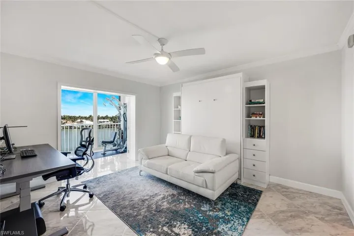 Office with light marble finish floors, ornamental molding, a water view, and a ceiling fan
