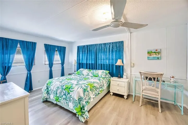 Bedroom with light wood finished floors, ceiling fan, and a textured ceiling