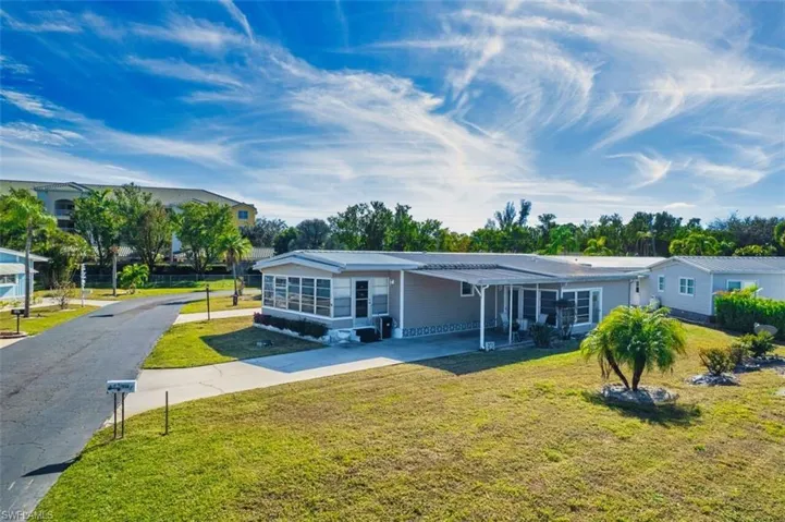 View of front of house with a carport, a front yard, concrete driveway, and a patio