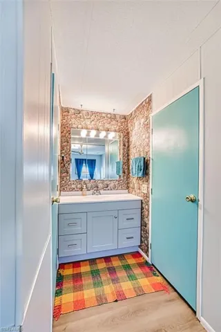 Bathroom with vanity, a textured ceiling, and light wood-style floors