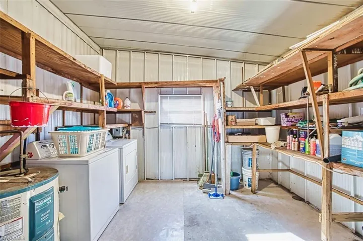 Washroom featuring metal wall, electric water heater, concrete flooring, and independent washer and dryer