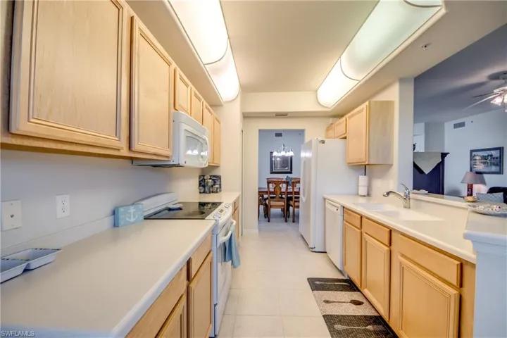 Kitchen featuring ceiling fan, light brown cabinetry, white appliances, sink, and light tile patterned floors