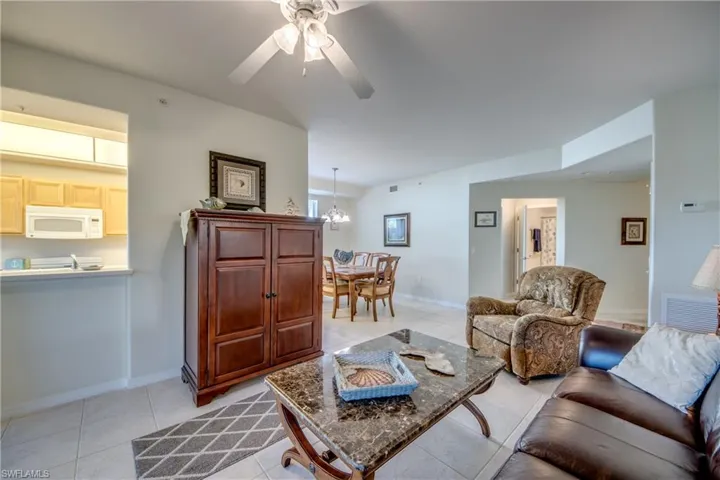 Tiled living room featuring ceiling fan with notable chandelier