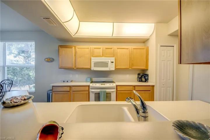 Kitchen featuring light brown cabinetry, sink, and white appliances