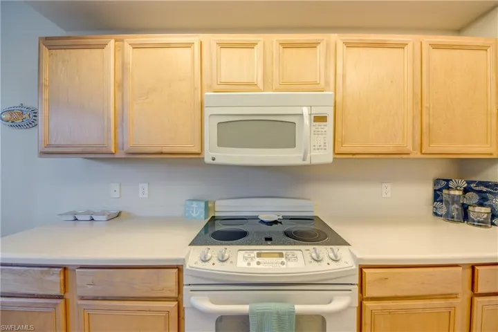 Kitchen with light brown cabinetry and white appliances