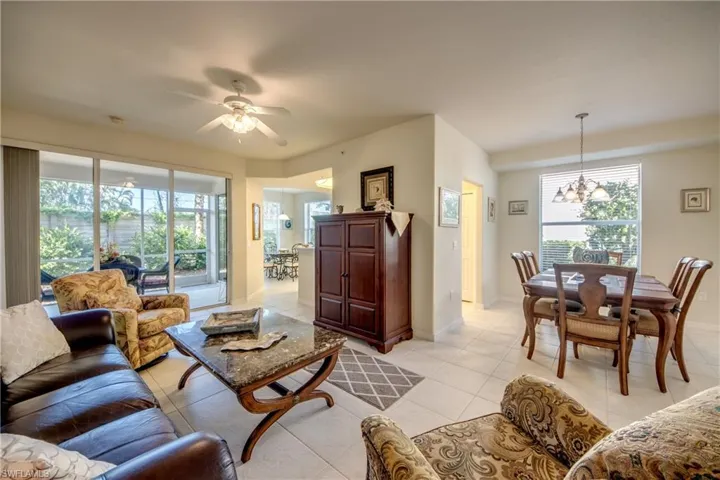 Tiled living room featuring plenty of natural light and ceiling fan with notable chandelier