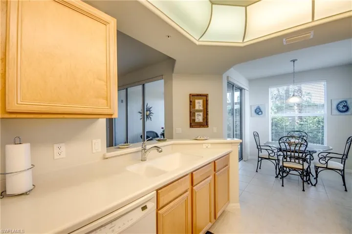 Kitchen with light tile patterned floors, a healthy amount of sunlight, light brown cabinetry, and sink