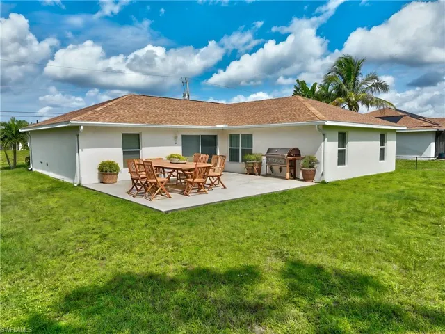 Rear view of property featuring area for grilling, a patio area, and a lawn (This photo was virtually staged)