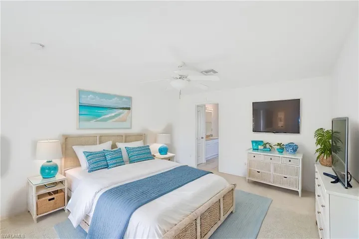 Carpeted bedroom featuring ceiling fan and ensuite bath (This photo was virtually staged)