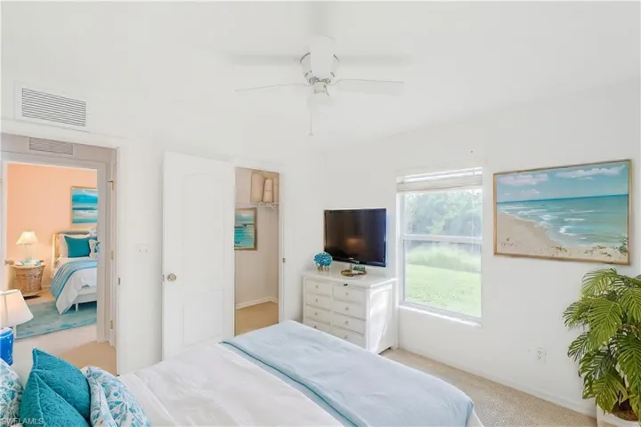 Carpeted bedroom with ceiling fan and walk in closet (This photo was virtually staged)