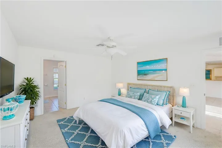 Bedroom featuring ceiling fan, connected bathroom, and light colored carpet (This photo was virtually staged)