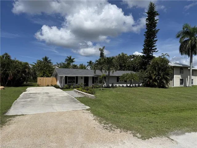 Single-story residence with a gray shingle roof, dark shutters, and a light-colored exterior
