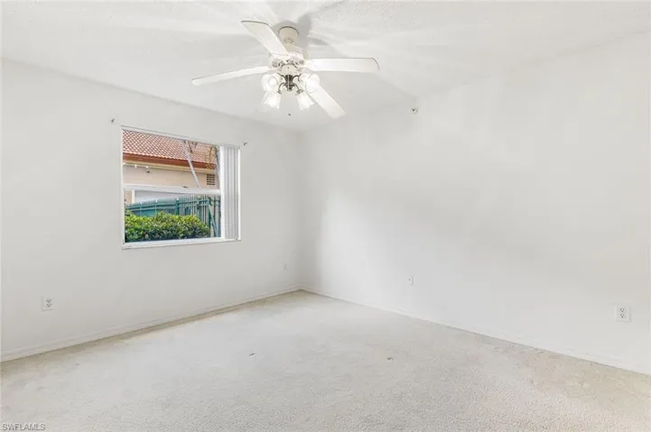 Bedroom with neutral wall colors, carpet flooring, ceiling fan, and large walk-in closet.