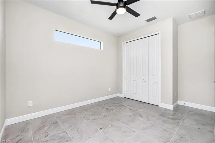 Unfurnished bedroom with a closet, ceiling fan, and light tile floors