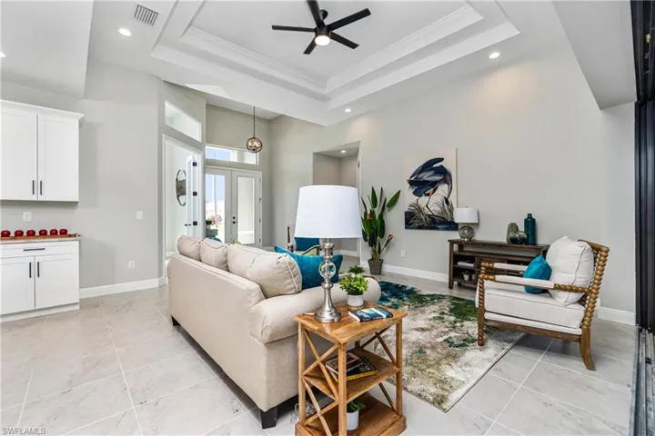 Tiled living room with a raised ceiling, ceiling fan, french doors, and a towering ceiling