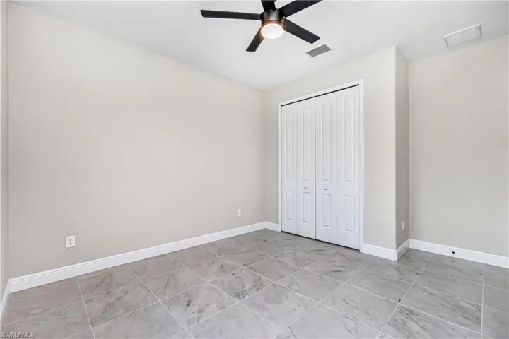 Unfurnished bedroom with a closet, ceiling fan, and light tile floors