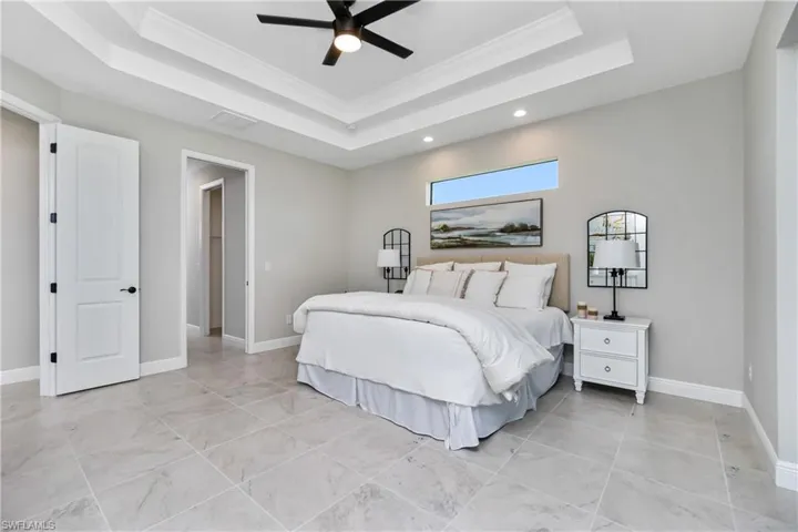 Tiled main bedroom featuring a raised ceiling and ceiling fan