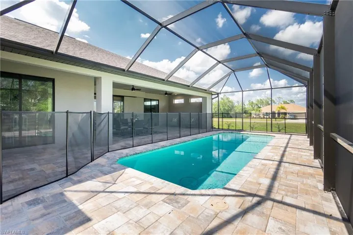 View of pool with ceiling fan, glass enclosure, and a patio area