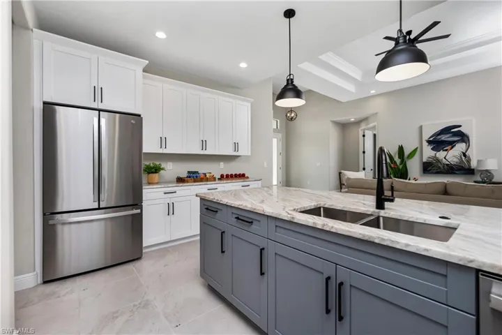 Kitchen featuring a raised ceiling, white cabinets, pendant lighting, and appliances with stainless steel finishes