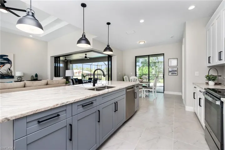 Kitchen featuring decorative light fixtures, white cabinets, sink, and light tile flooring