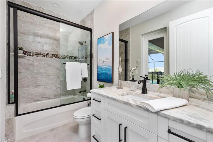 Full bathroom featuring tile floors, vanity, toilet, and bath / shower combo with glass door