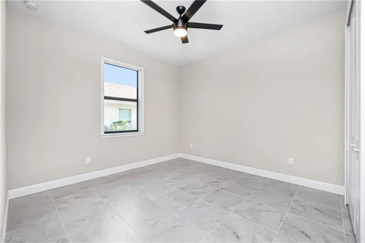 Spare room with ceiling fan and light tile flooring