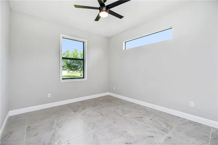 Tiled guest bedroom featuring plenty of natural light and ceiling fan