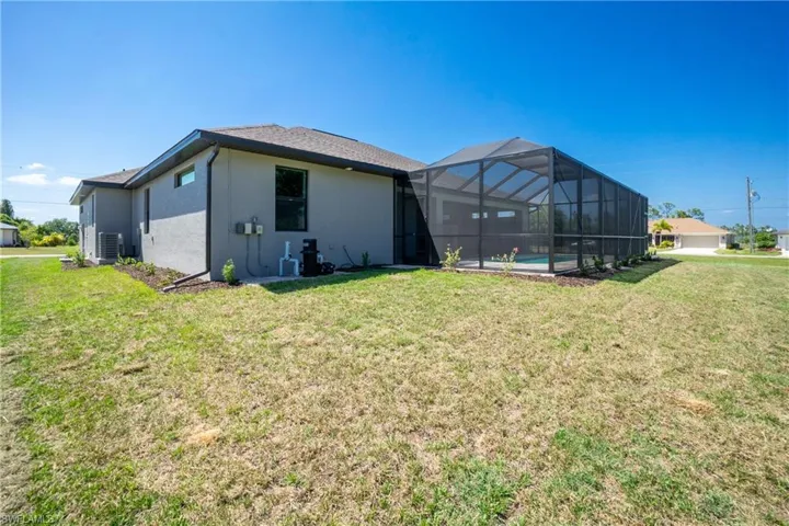 Back of house featuring a lawn, central AC unit, and a lanai
