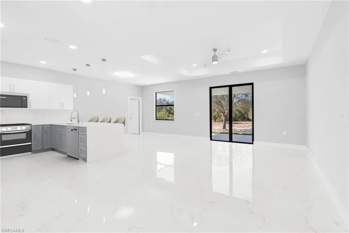 Unfurnished living room with a tray ceiling and ceiling fan