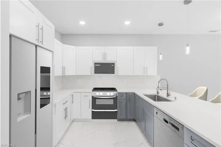 Kitchen with gray cabinetry, white cabinets, and hanging light fixtures