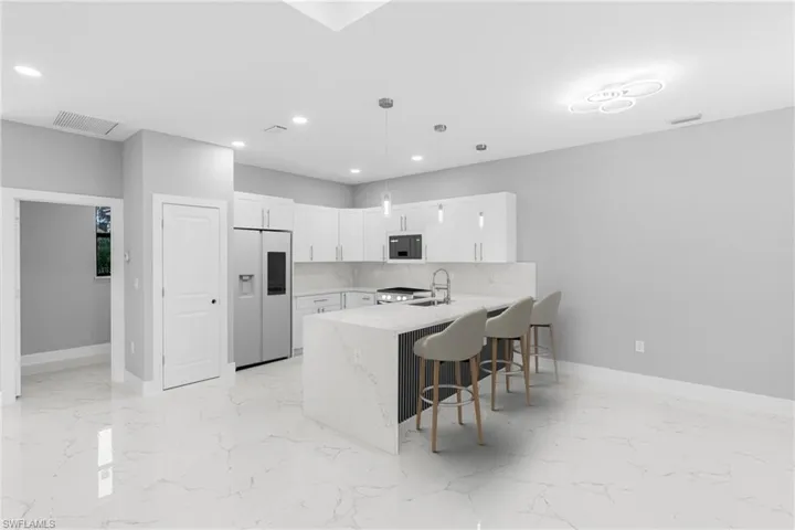 Kitchen with white appliances, sink, kitchen peninsula, tasteful backsplash, and white cabinetry