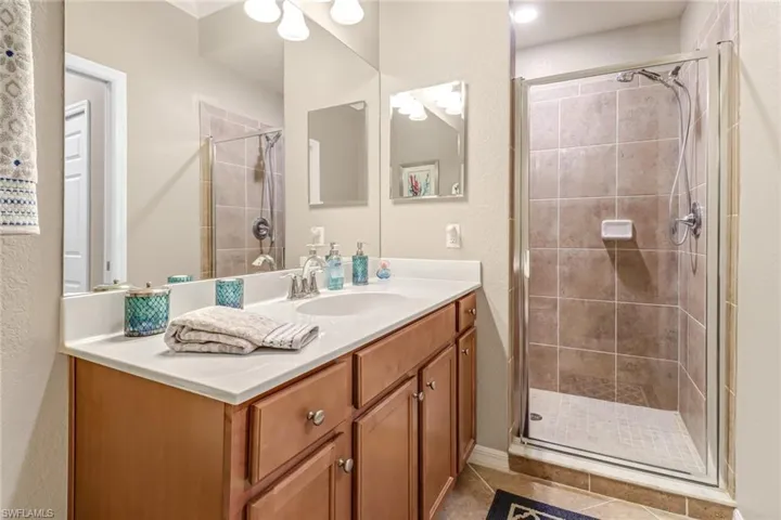 Bathroom featuring walk in shower, tile patterned flooring, and vanity