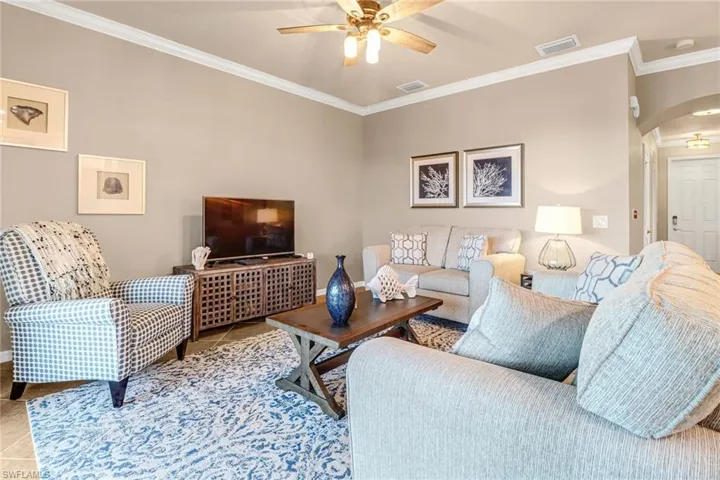 Living room featuring ornamental molding, tile patterned floors, and ceiling fan