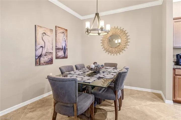 Tiled dining space featuring crown molding and a chandelier
