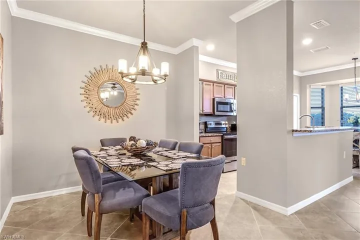 Tiled dining area featuring ornamental molding, a notable chandelier, and sink