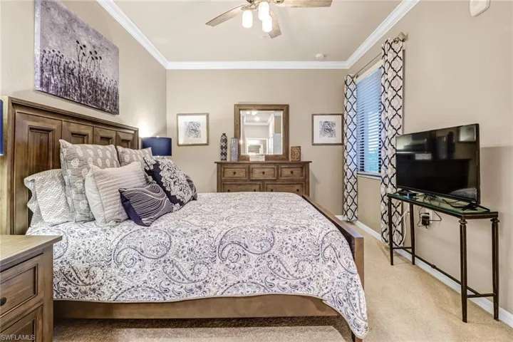 Carpeted bedroom featuring ornamental molding and ceiling fan