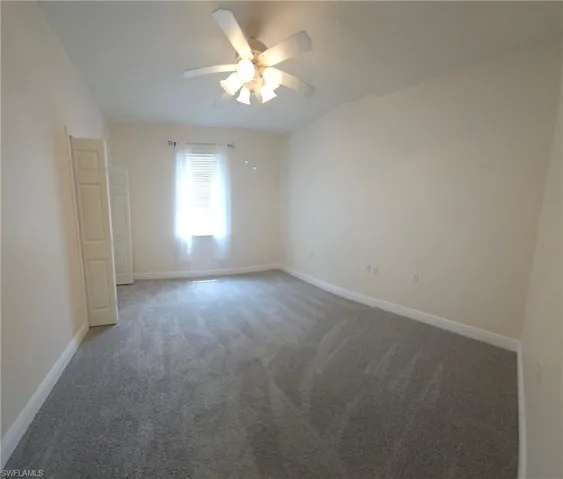 Carpeted empty room with ceiling fan