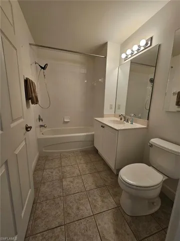 Full bathroom with tile floors, tiled shower / bath, toilet, and vanity