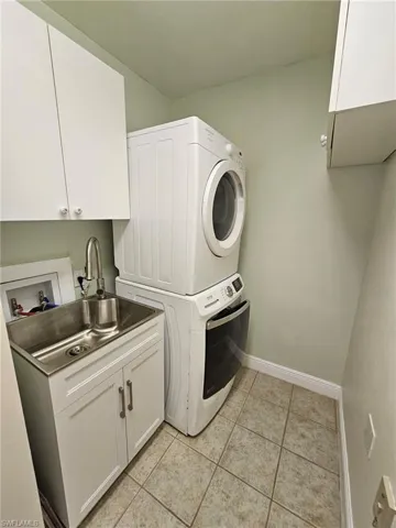 Laundry area featuring cabinets, light tile flooring, washer hookup, and stacked washer and dryer